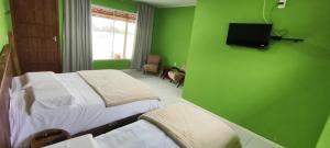 a green room with two beds and a tv on the wall at Hotel Serra Catarinense in Bom Retiro
