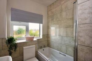 a bathroom with a tub and a toilet and a window at 33 Beautiful 2 bed apt Tamworth Private Parking in Fazeley