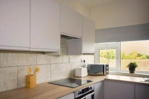 a kitchen with white cabinets and a microwave at 33 Beautiful 2 bed apt Tamworth Private Parking in Fazeley +10 photos