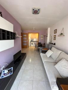 Una sala de estar con un sofá blanco y una cocina. en apartamento a 5 minutos playa andando, en Torredembarra