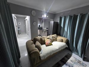 a couch in a living room with green curtains at Upendorest in Gaborone