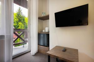 uma sala de estar com uma televisão de ecrã plano e uma janela em FAMILIJNY Ośrodek Wypoczynkowy Krynica Zdrój em Krynica Zdrój