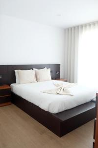 una camera da letto con un letto grande con lenzuola bianche di Olive House - 4 bedrooms a Gafanha da Nazaré