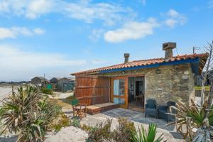 a small stone house with a blue roof on the beach at Sea Hut Apulia in Apúlia