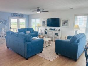 a living room with two blue couches and a tv at Libby's Lookout in Holden Beach