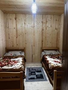 two beds in a room with wooden walls at Bata GuesThouse in Adishi