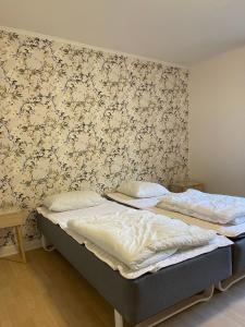 2 camas individuales en una habitación con papel pintado en The Gatekeepers Cottage at Hindemae Estate Cozy Stay in Historic Surroundings, en Ullerslev
