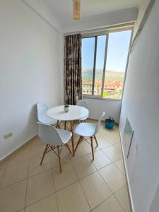 une table blanche et des chaises dans une pièce avec une fenêtre dans l'établissement Deir Apartment, à Berat