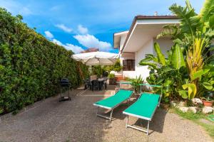 un patio con 2 bancos y una sombrilla en The Rosa's Luxury House, en Alezio