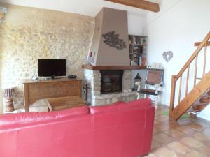 Saint-Montan的住宿－Le Mouleyras，客厅设有红色的沙发和壁炉