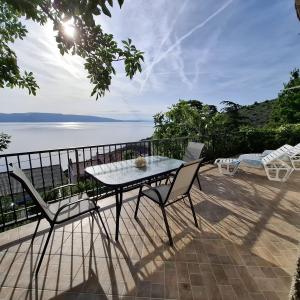 a table and chairs on a patio with a view of the water at Apartment Loza Senj in Senj