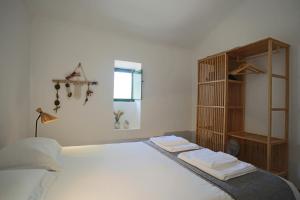 a bedroom with a white bed with a book shelf at Tapada da Figueira by NaturAlegre in Esperança