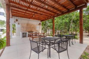 a patio with tables and chairs under a wooden pergola at RayoDeSol Condo10min to Beach,Gym,Pool,WIFI 200MB in Playa del Carmen