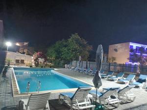 a swimming pool at night with chairs and a swimming pool at Vila Andra in Costinesti