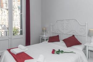 a white bed with red pillows and roses on it at Whatching Sagrada Familia in Barcelona