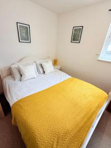 a bedroom with a bed with a yellow blanket on it at Penthouse with City Views in Bristol