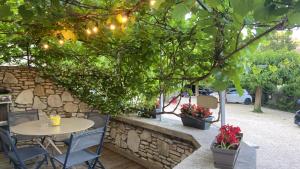 a patio with a table and chairs under a tree at Chambres La Vieille Source in Saint-Martin-dʼArdèche