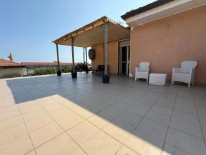 Un patio con dos sillas blancas y una carpa. en Martina house, en Camporosso