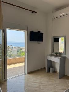 a living room with a sliding glass door and a television at Vila Alexandros in Qeparo