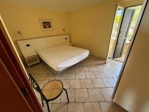 een kleine slaapkamer met een bed en een stoel bij Residence IL BORGO 37 in Tortoreto Lido