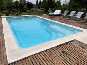 a large swimming pool with chairs on a deck at Gîte Villa Santina in Piquecos
