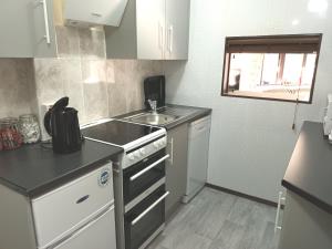 a small kitchen with a sink and a stove at The Chantry, North Wing, Cottage in Hemsby