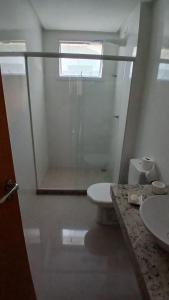 a bathroom with a toilet and a sink and a window at Cozy Apartment in Domingos Martins