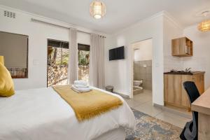 a white bedroom with a bed and a bathroom at ZinziLuxe Guest House in Johannesburg