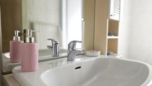a bathroom sink with two soap dispensers and a mirror at Al Ludomar, Cozy Flat and Free Park in Rapallo