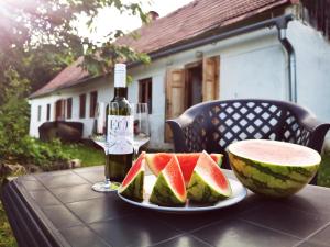 a table with a plate of watermelon and a bottle of wine at Ubytovanie Domček Paradajz in Banská Štiavnica +16 photos