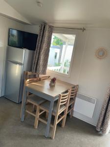 瓦尔拉普拉日Mobil Home CAMPING LES SABLES DU MIDI的带窗户的厨房里的桌椅