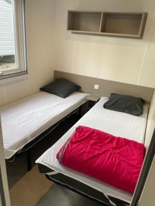 瓦尔拉普拉日Mobil Home CAMPING LES SABLES DU MIDI的小客房内的两张床,配有红色床单 更多11张照片