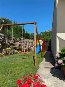 a playground with swings in a yard with flowers at Jacuzzi House Kaštela - Parking - Playground in Kaštela