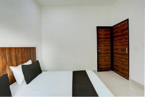 a bedroom with a white bed and a wooden door at Hotel O Rajhans in Gurgaon +38 photos