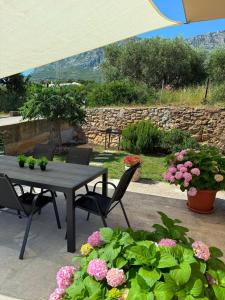 a patio with a table and chairs and flowers at Jacuzzi House Kaštela - Parking - Playground in Kaštela