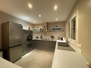 una cucina con frigorifero in acciaio inossidabile e armadietti grigi di Magnifique villa avec piscine a Perpignano