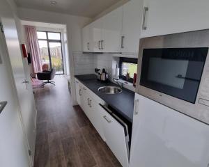 a kitchen with white cabinets and a sink and a microwave at Enkhuizer Strandchalet Nr 257 in Enkhuizen +8 photos