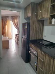 eine Küche mit einem schwarzen Kühlschrank und Holzschränken in der Unterkunft شالية في كمباوند سكانديك عرابيا in Hurghada