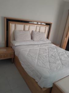 ein großes Bett mit weißen Laken und Kissen in der Unterkunft شالية في كمباوند سكانديك عرابيا in Hurghada + 8 Fotos