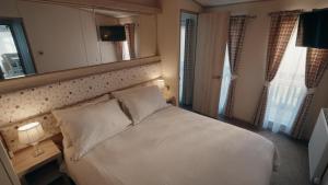 a bedroom with a white bed and a mirror at New Forest Retreat on a Holiday Park in New Milton