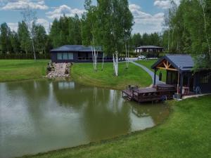 a lake with a gazebo next to a house at Žalesos pirtelė in Ažulauke
