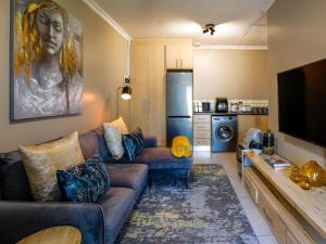 Una sala de estar con un sofá y un televisor. en La Petit Bordeaux, en Johannesburgo