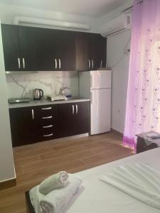 Una cocina con gabinetes negros y un refrigerador blanco. en Guesthouse Sueda, en Ksamil