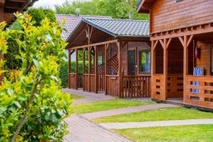 a large wooden cabin with a porch and grass at ROSSA - Domki Letniskowe in Międzywodzie