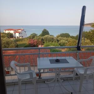 a white table and chairs on a balcony with the ocean at House Mantesos in Koinyra