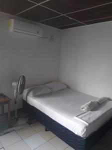 a white bed in a room with a fan at Hostal don Frank in San Carlos