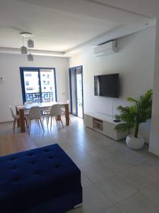 a living room with a table and a tv on a wall at Appartement Costa Mar Martil in Martil