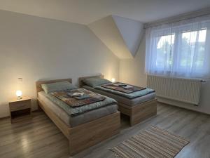 a bedroom with two beds and a window at Ubytovanie PLATAN in Bartošovce