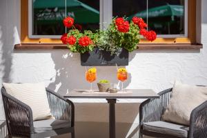 a table with two glasses and flowers on a patio at Hotel Pettneuerhof in Pettneu am Arlberg