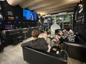 a group of people sitting in a bar watching tv at Andaman Genetics 420 Rooms in Ao Nang 